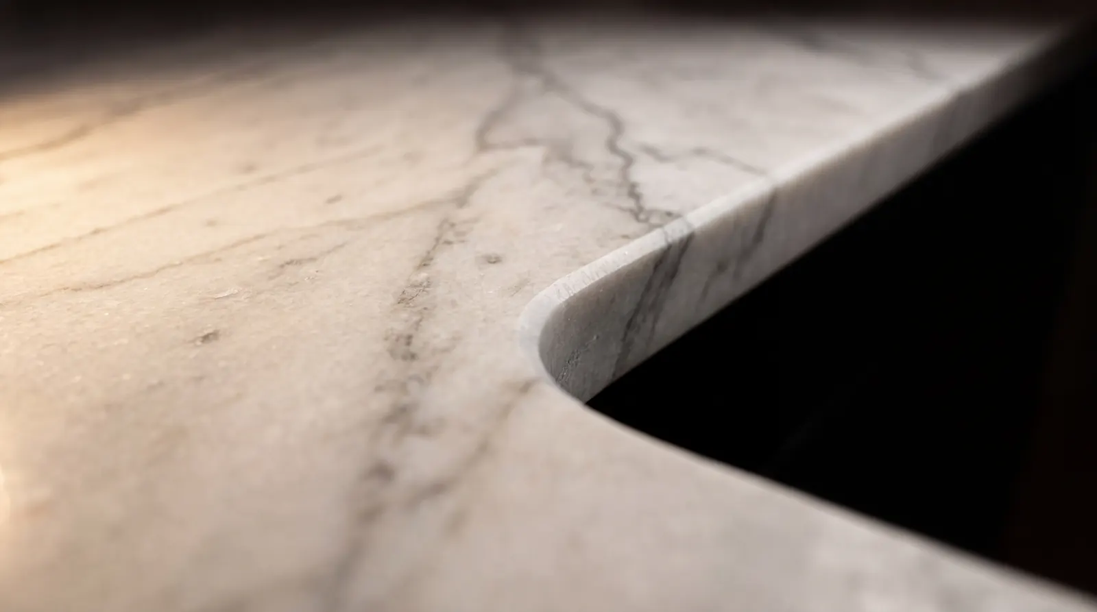 Honed white marble countertop edge in warm raking light